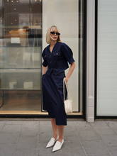 a lady wears a denim v-neck top and midi skirt